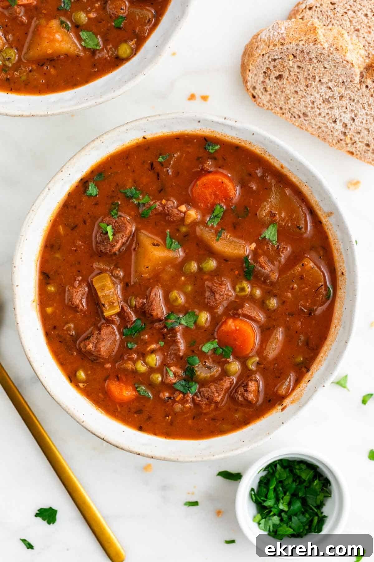 Hearty Vegan Beef-Style Stew with Plant-Based Chunks 2 Vegan beef stew served in a bowl with bread and parsley around it.