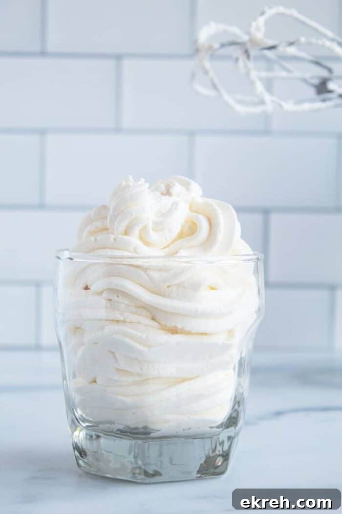 3-Ingredient Keto Whipped Cream Recipe 14 keto whipped cream in a glass cup in front of mixing beaters