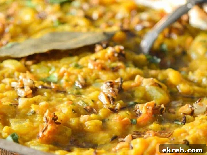 A silver bowl with dal tadka in it