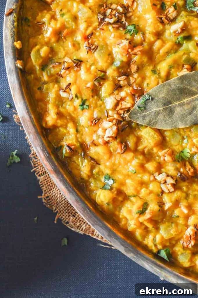 25-Minute Restaurant-Style Dal Tadka Recipe 3 A close up of yellow lentil curry with cumin and a bay leaf on top
