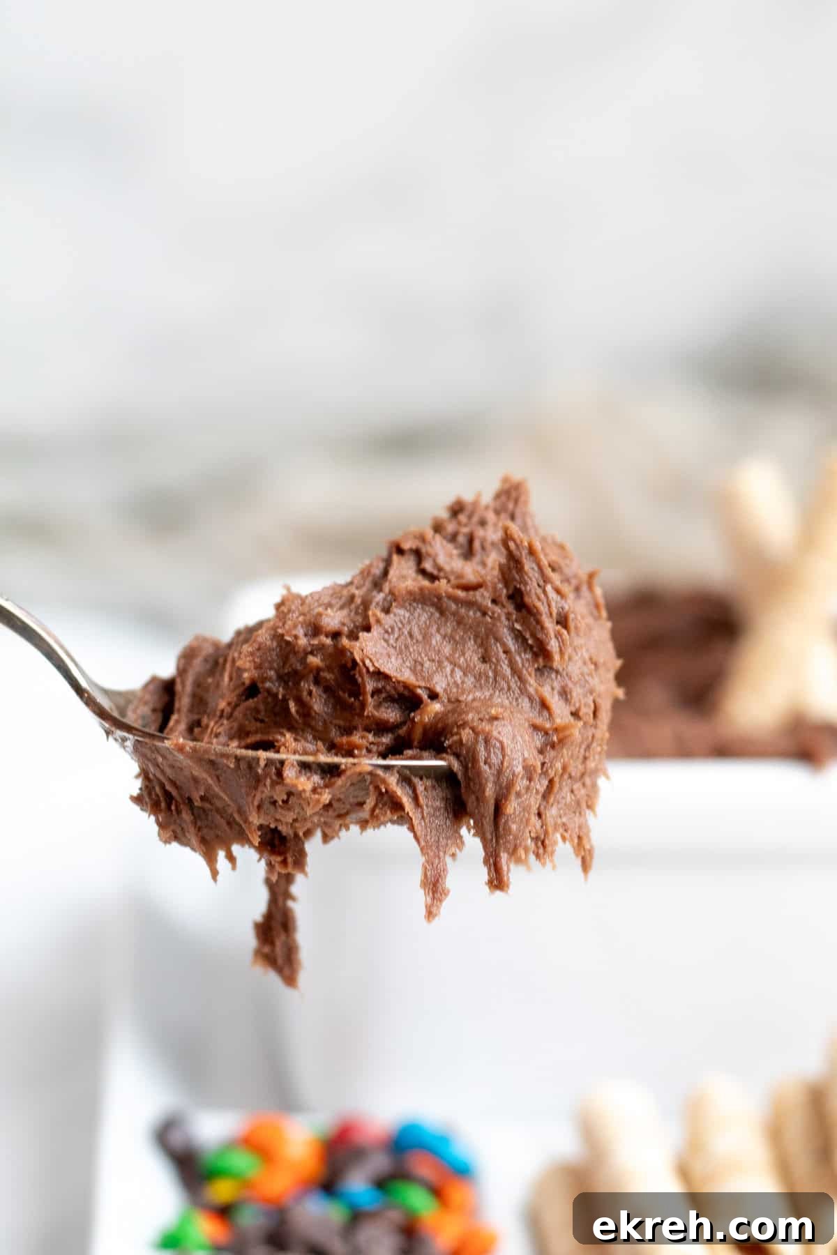 brownie dip on a spoon with a platter of topping in background