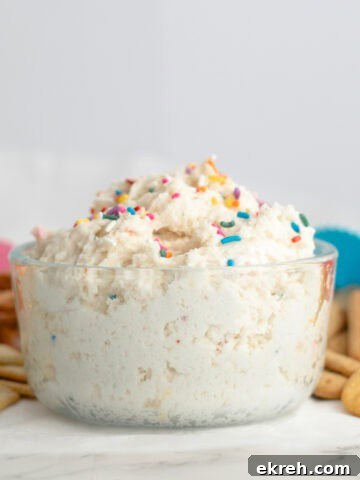 funfetti dip in a glass bowl with sprinkles surrounded by dipping options