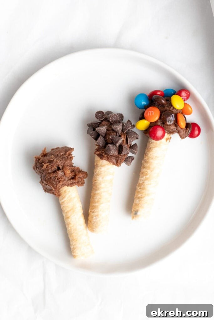 three wafer cookies dipped in brownie batter with toppings.