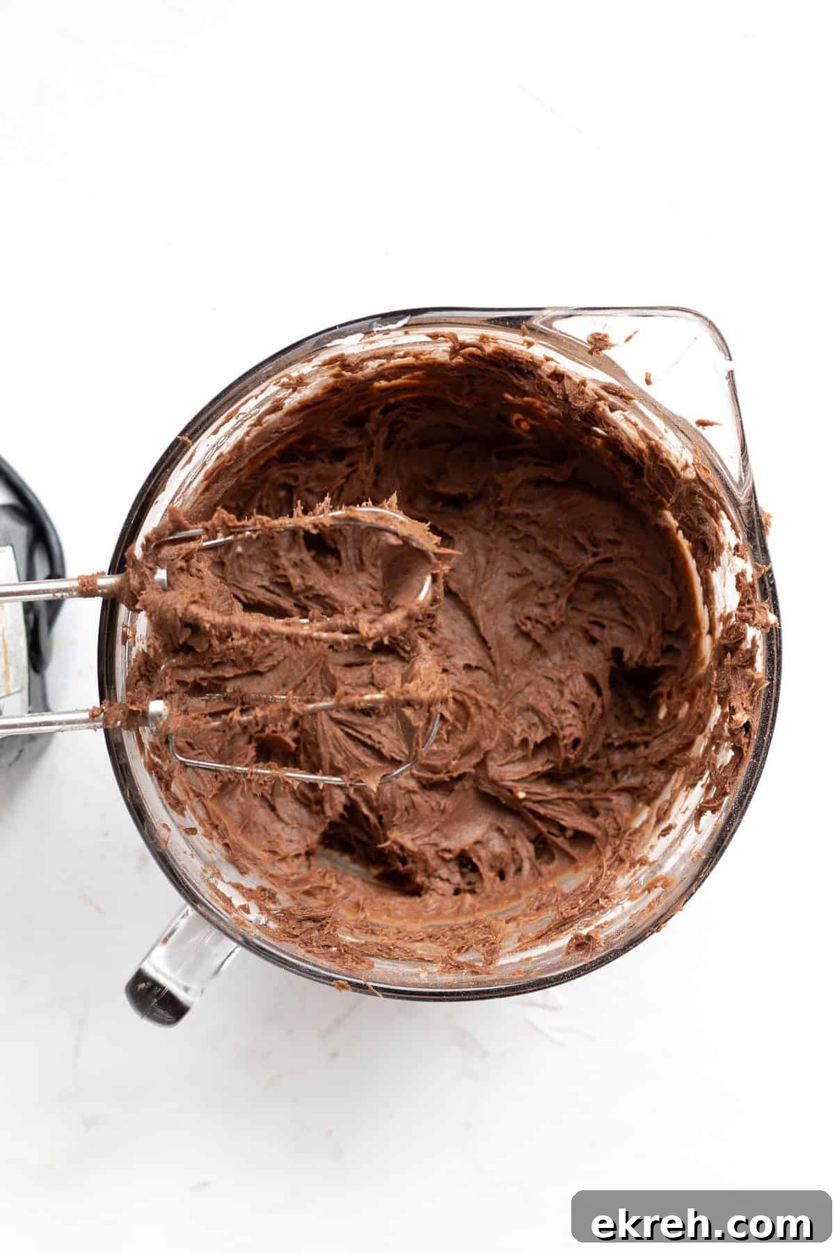 brownie batter in a glass mixing bowl with electric mixer