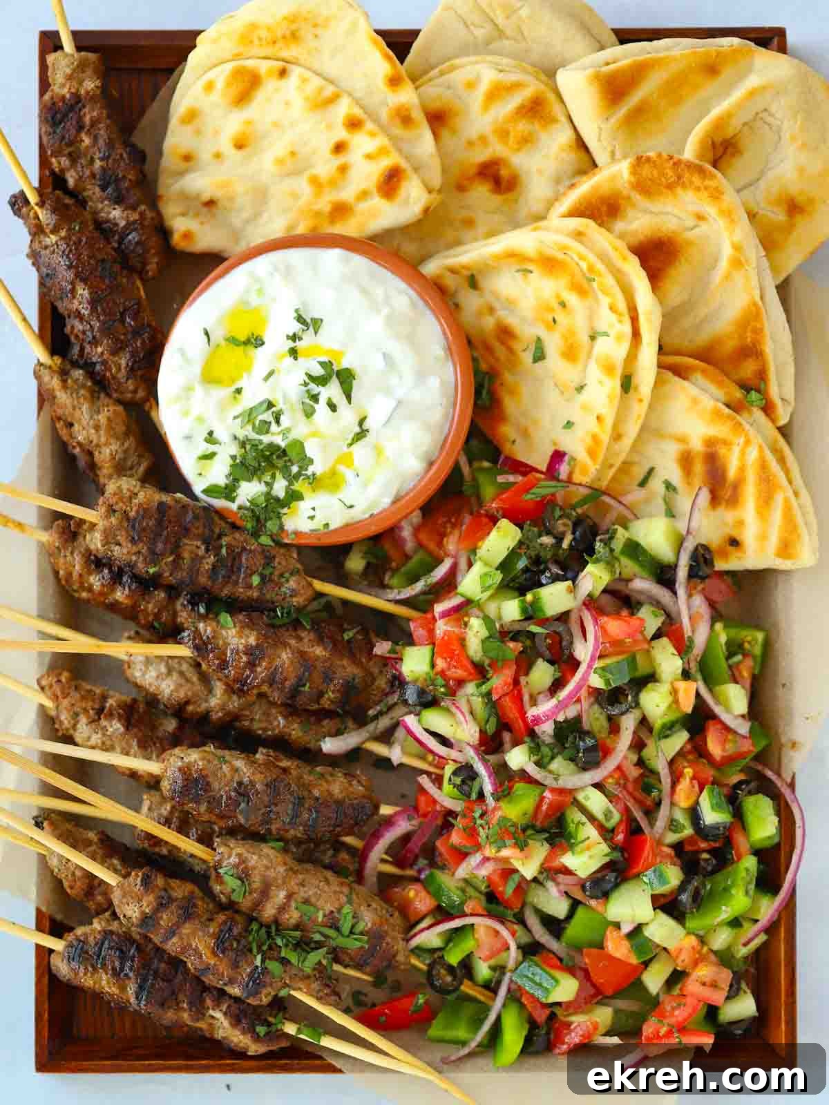 Spiced Lamb Koftas with Tzatziki Sauce 2 Lamb koftas recipe with meat mince and tzatziki, on a tray with flatbreads.