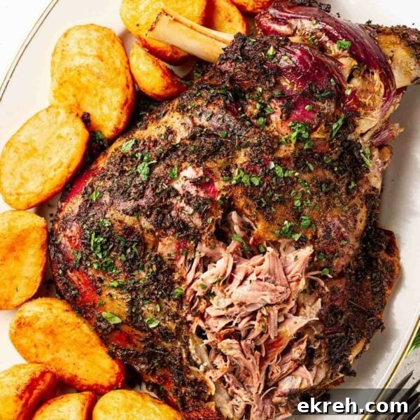 Roast lamb shoulder with a herb rub, next to roast potatoes.