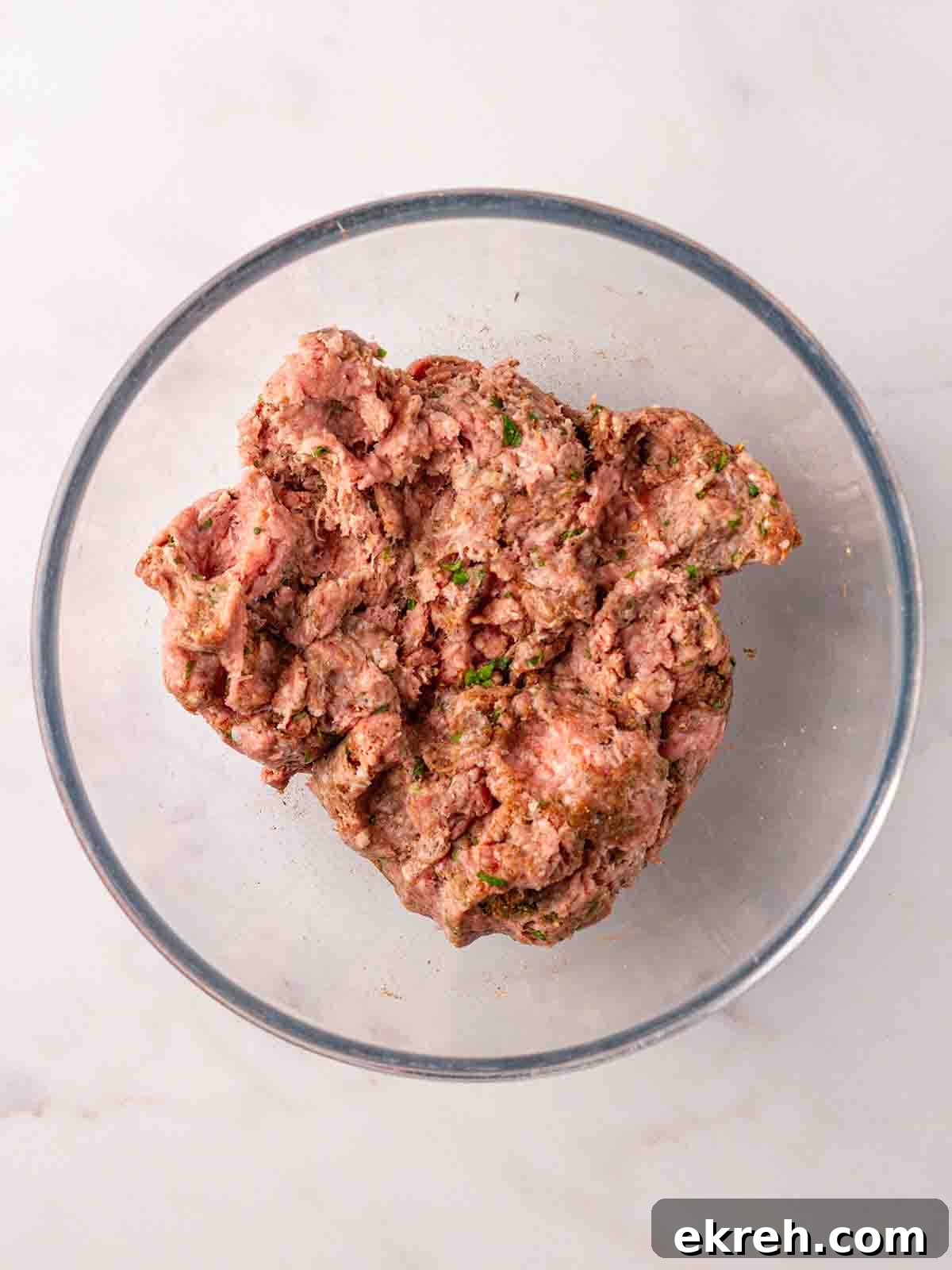 Spiced Lamb Koftas with Tzatziki Sauce 8 Raw lamb mince mixed with herbs in a glass bowl, ready to be turned into kebabs.