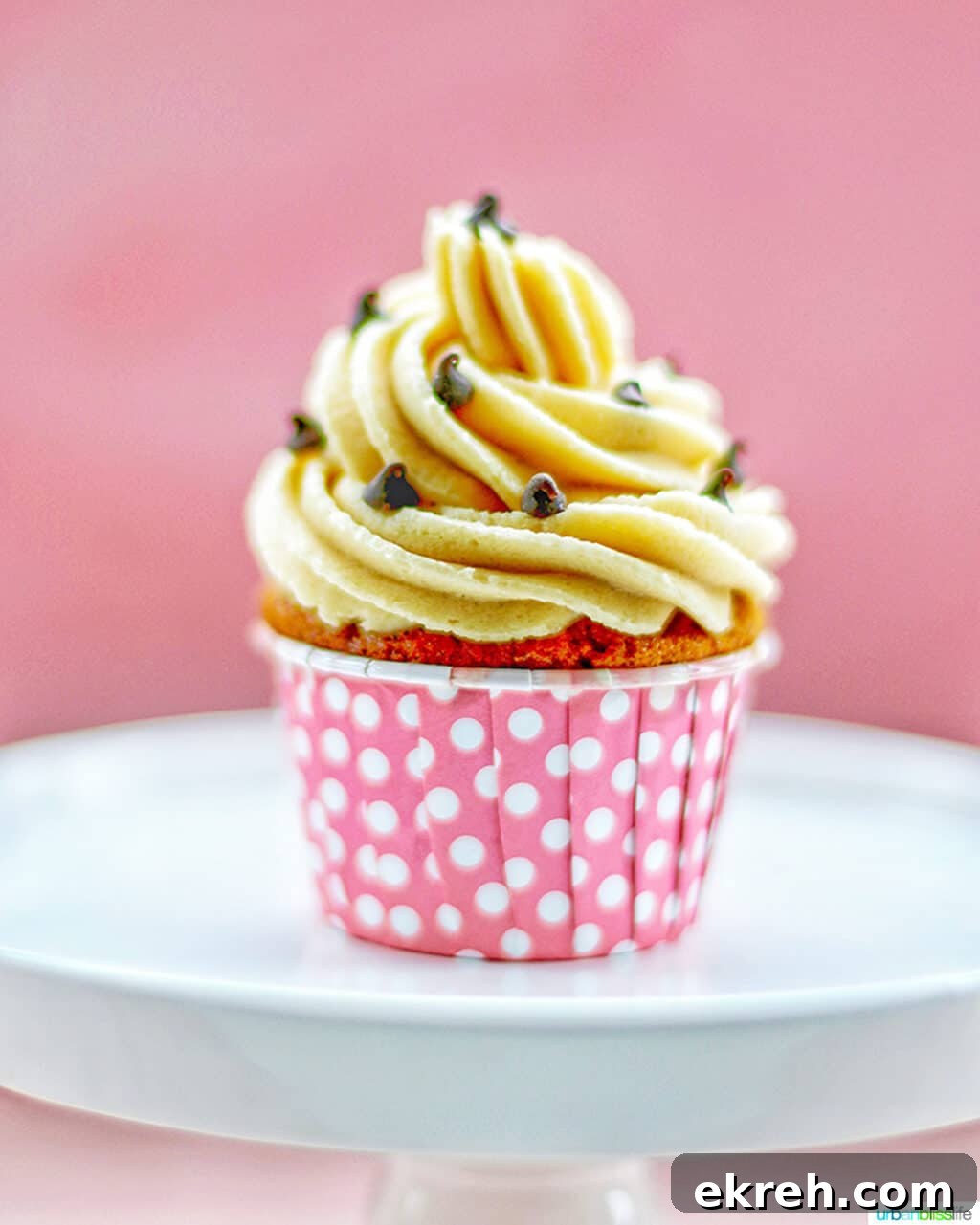 Chocolate Chip Cupcakes with Cookie Dough Frosting Recipe 13 one chocolate chip cupcake with cookie dough frosting in pink cup on white cake pedestal
