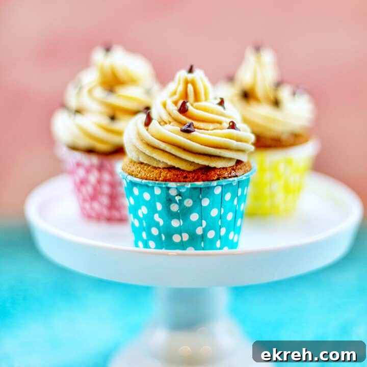 Chocolate Chip Cupcakes with Cookie Dough Frosting Recipe 19 chocolate chip cupcakes with cookie dough frosting in blue, pink, and yellow cups on a pedestal.