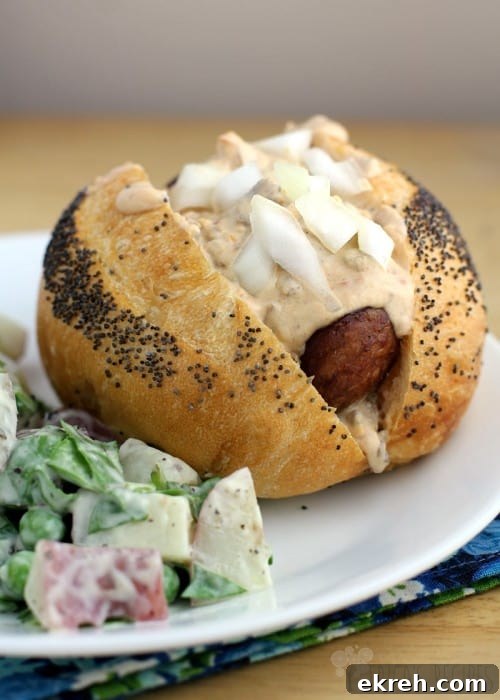 angled view of the finished Grilled Beer Kielbasa with Sausage and Stout Queso, topped with onions, on a white place with a bit of salad on the side