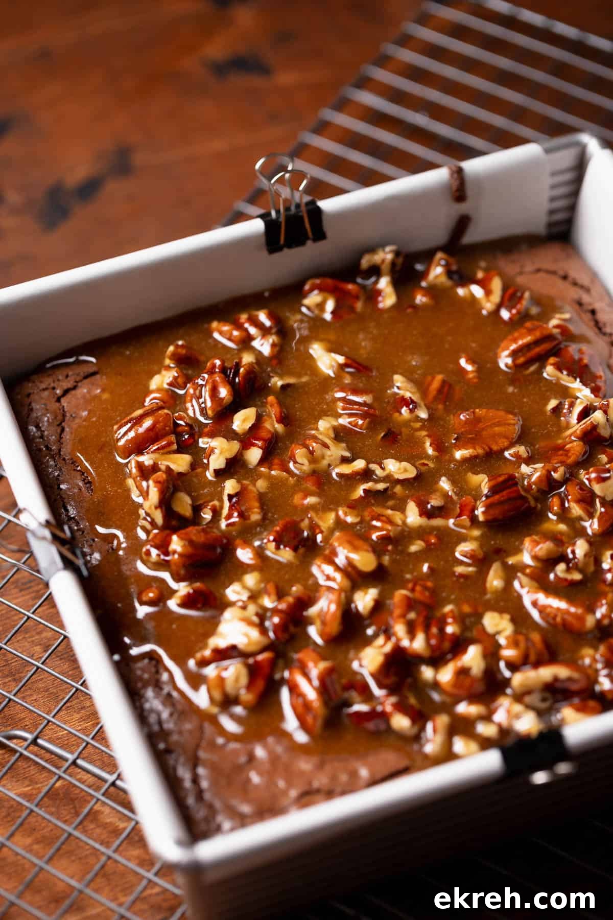 The pecan filling being poured over the top of the baked brownie.
