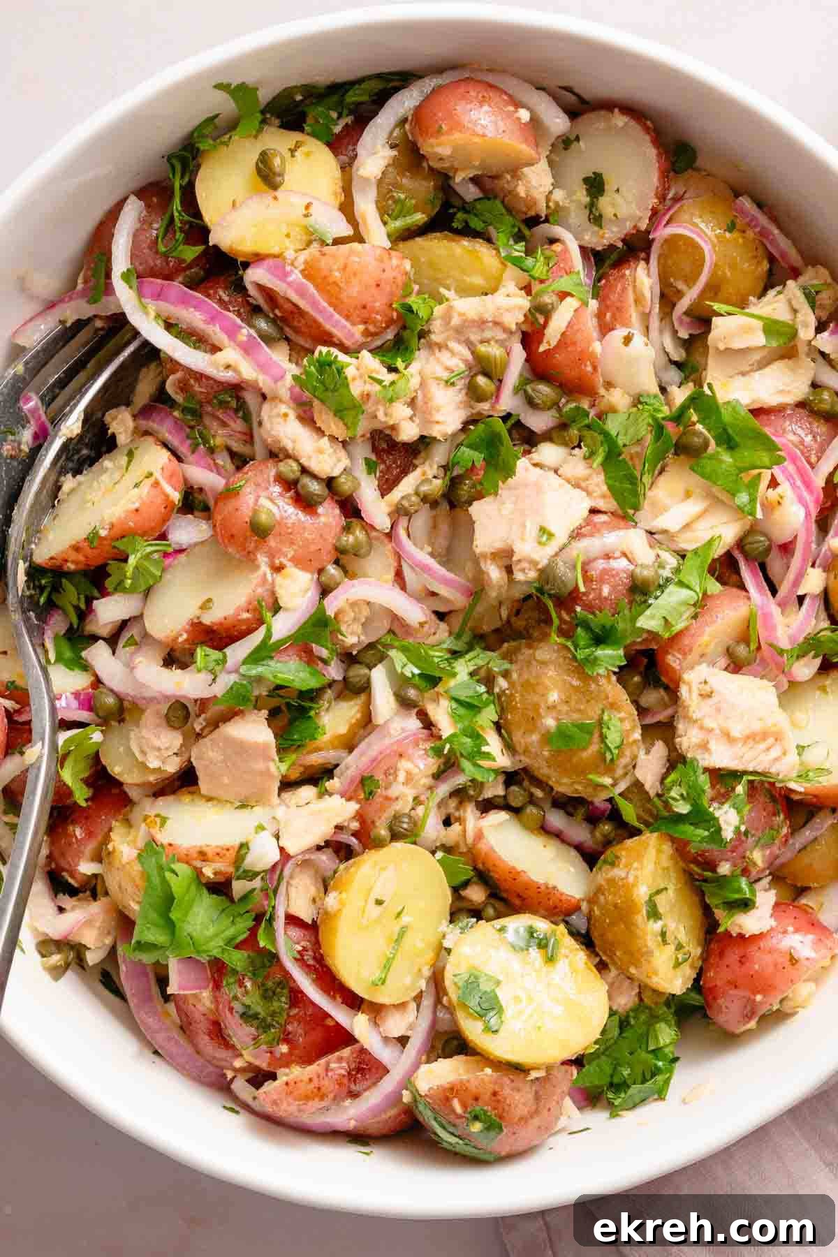 Classic Tuna and Potato Salad Recipe 2 potato salad with tuna and red onions in white bowl.