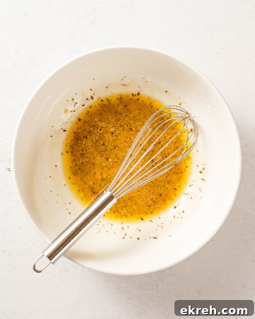Classic Tuna and Potato Salad Recipe 6 dressing in white bowl with whisk.