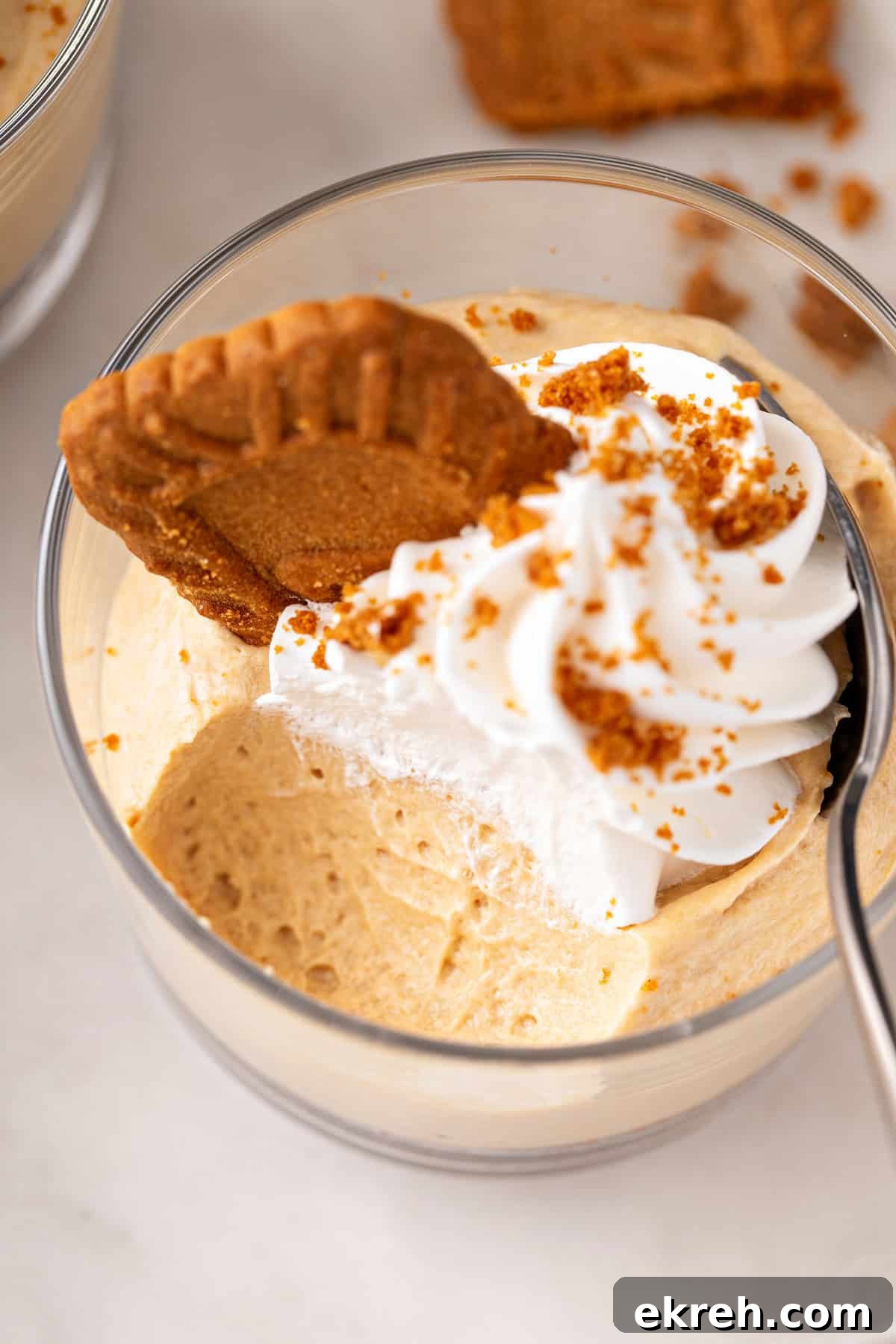 Bite taken from no-bake biscoff cheesecake in a glass ramekin.
