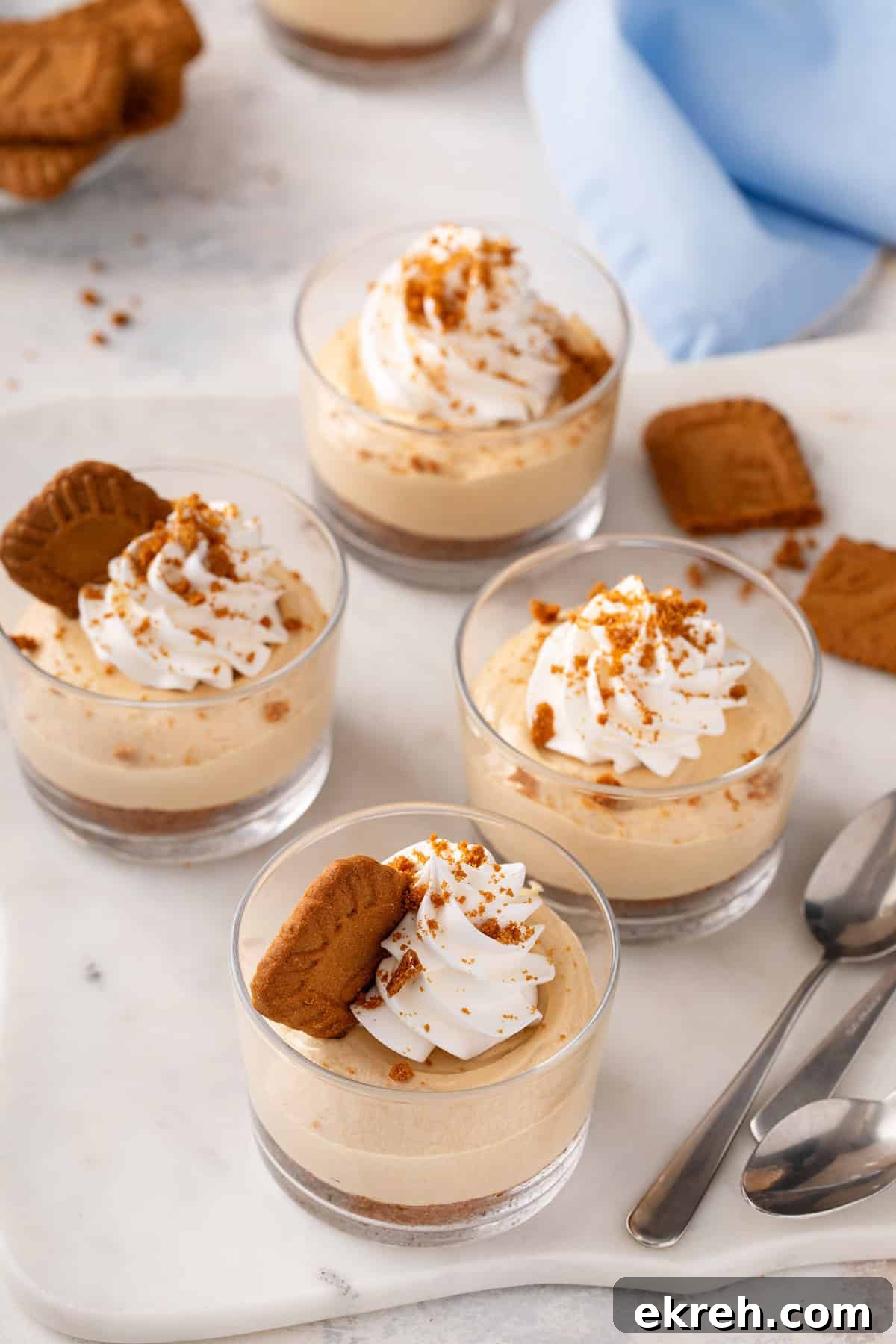 Four ramekins of no-bake biscoff cheesecake arranged on a marble board.