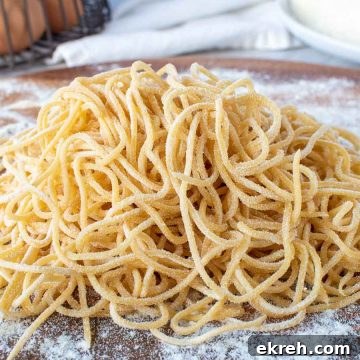 pile of yellow homemade spaghetti on wooden board.
