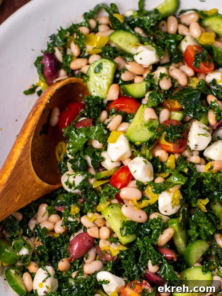 close up view of kale and cannellini bean salad with a wooden spoon