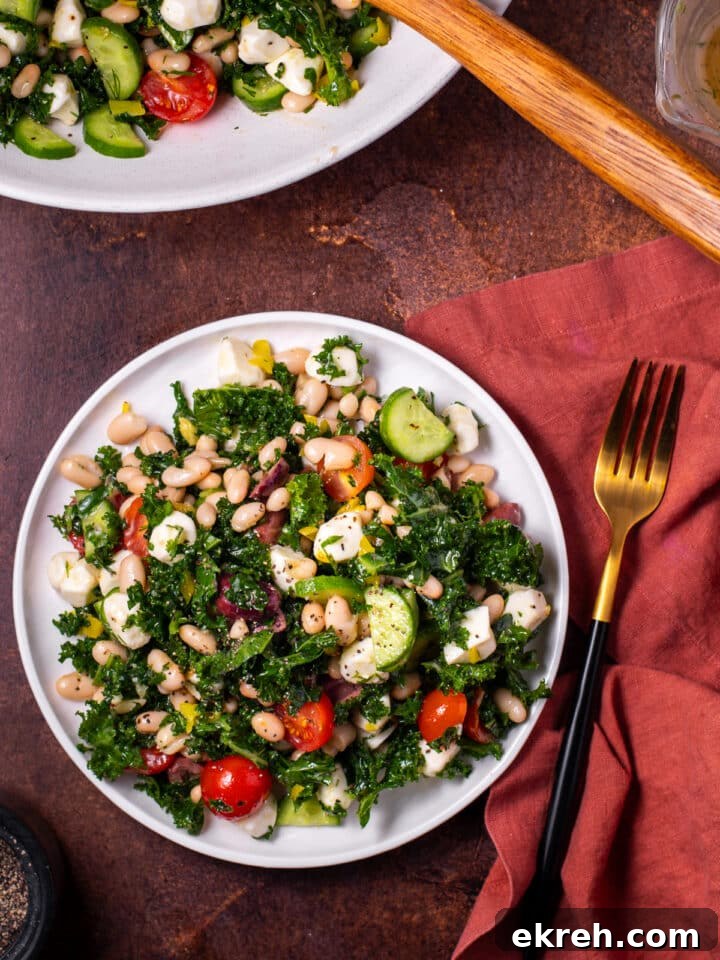 kale and cannellini bean salad on a small white plate, gold fork, red napkin