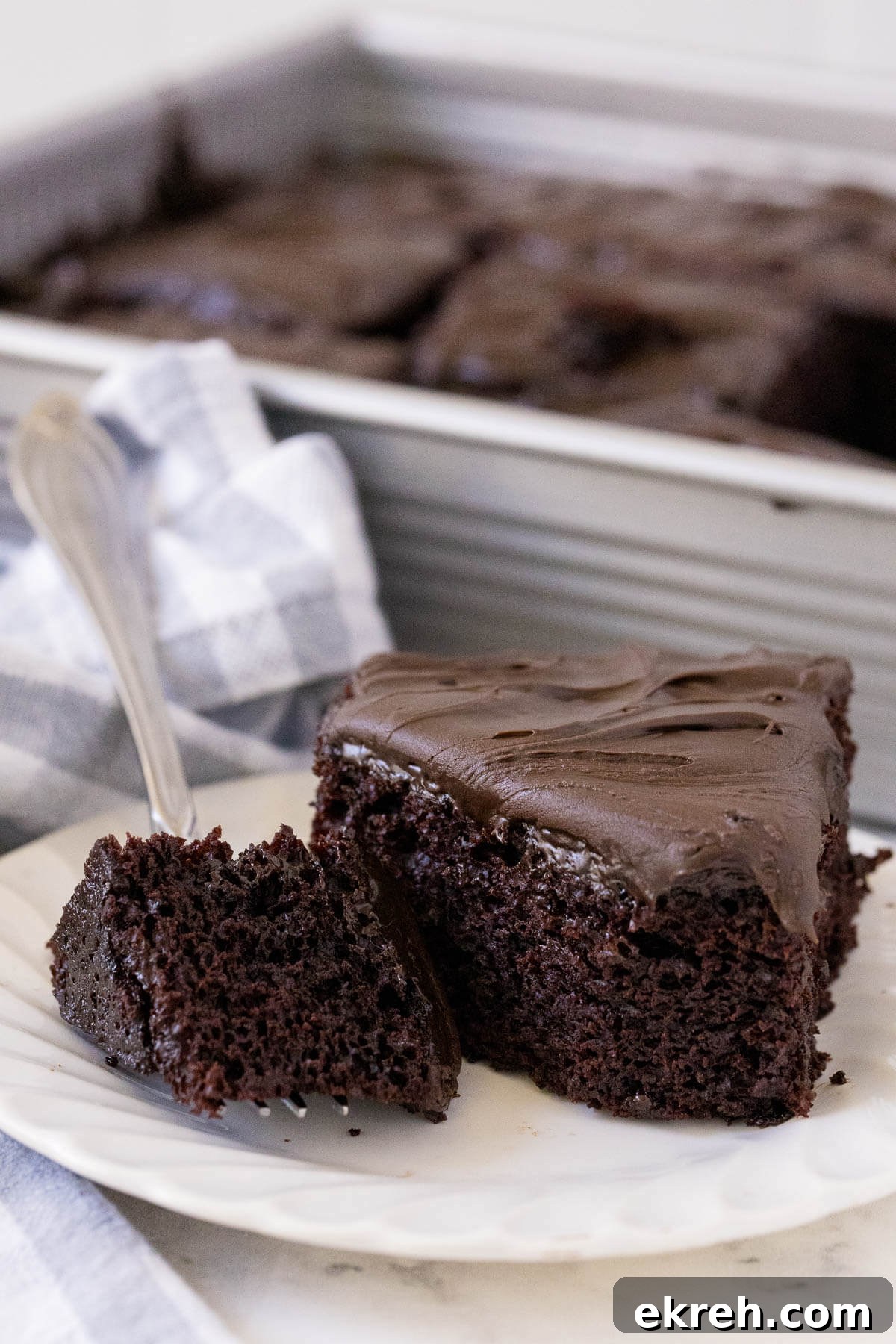 A piece of cake on a plate with a piece on a fork.