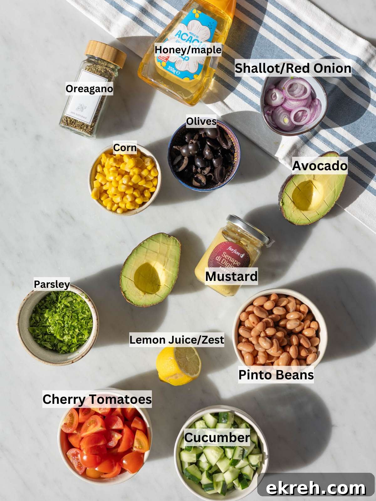 Ingredients for pinto bean salad on marble table with fresh vegetables and herbs in natural light.