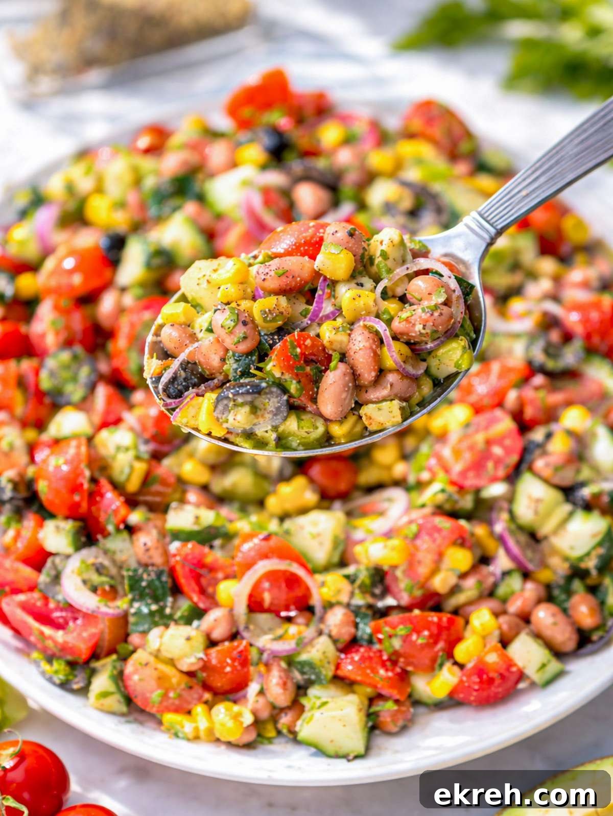Close up of pinto bean salad showing creamy beans, juicy tomatoes, and fresh parsley.