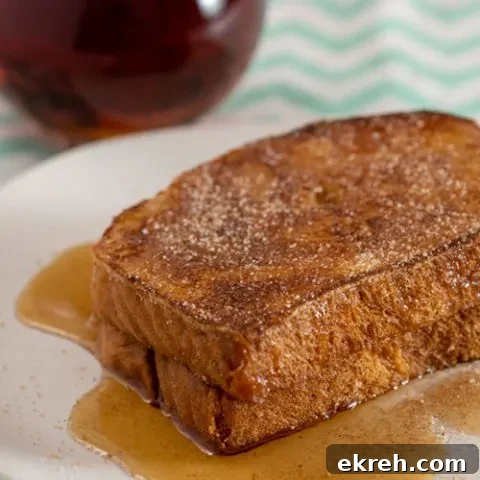 Two slices of churro French toast in front of a pitcher of syrup