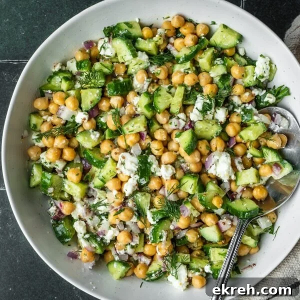 Cucumber chickpea and feta chopped salad in a bowl garnished with dill.