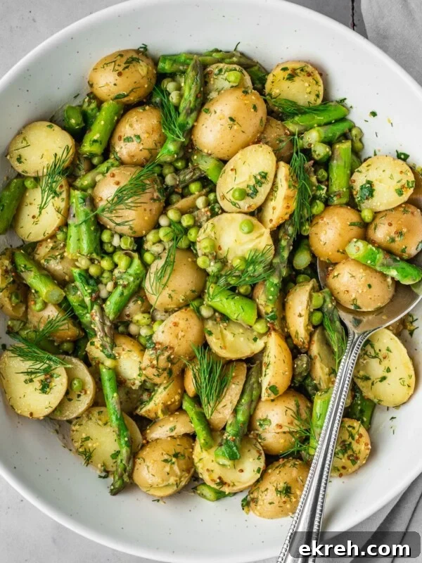 Asparagus pea potato salad in a large serving bowl garnished with dill.