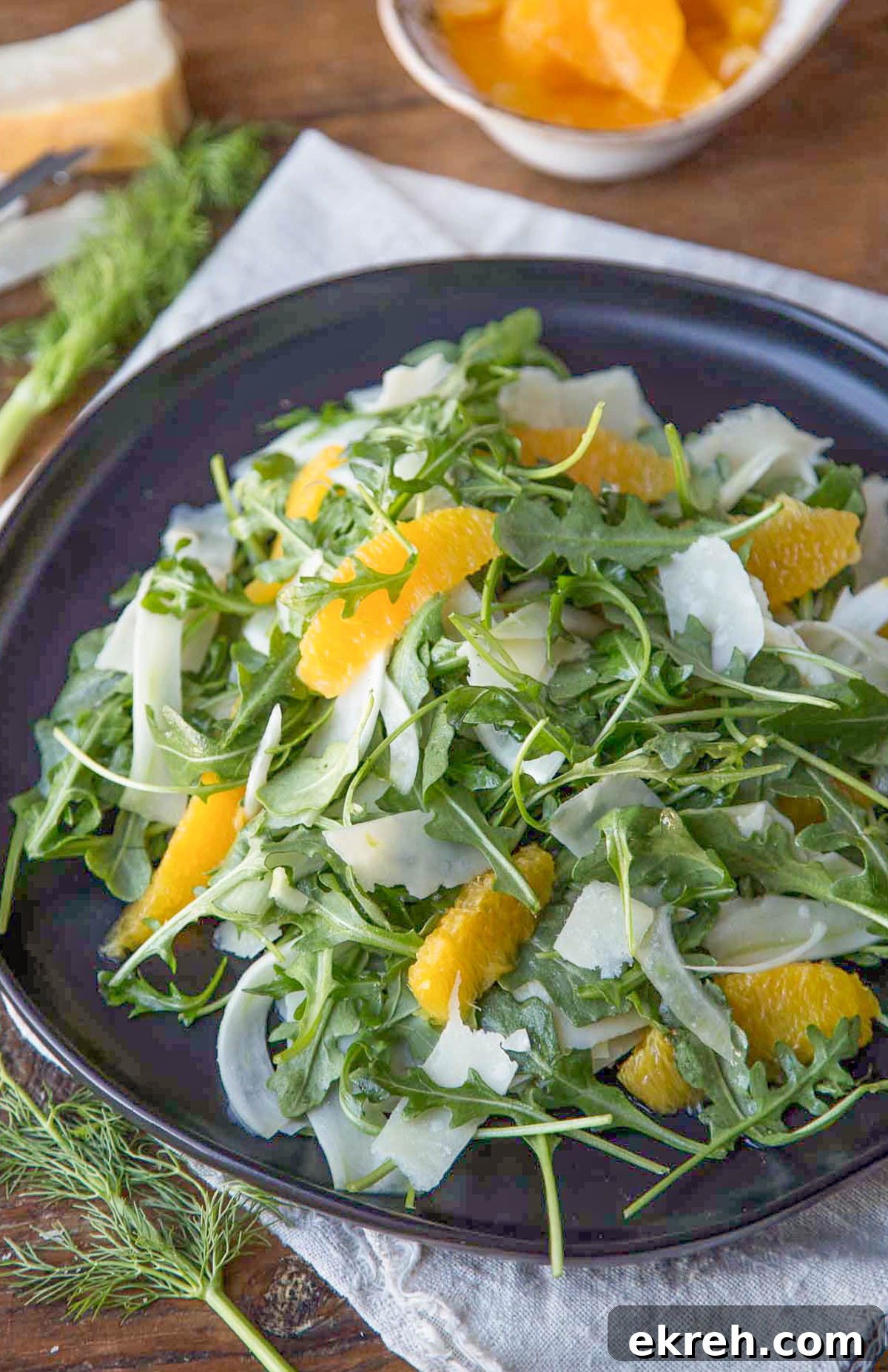 Fennel, Orange and Arugula Salad 2 fennel and orange salad with arugula and shaved parmesan on a black plate.