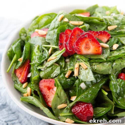 Fennel, Orange and Arugula Salad 7 strawberry spinach salad topped with almonds and sliced strawberries in a white bowl.