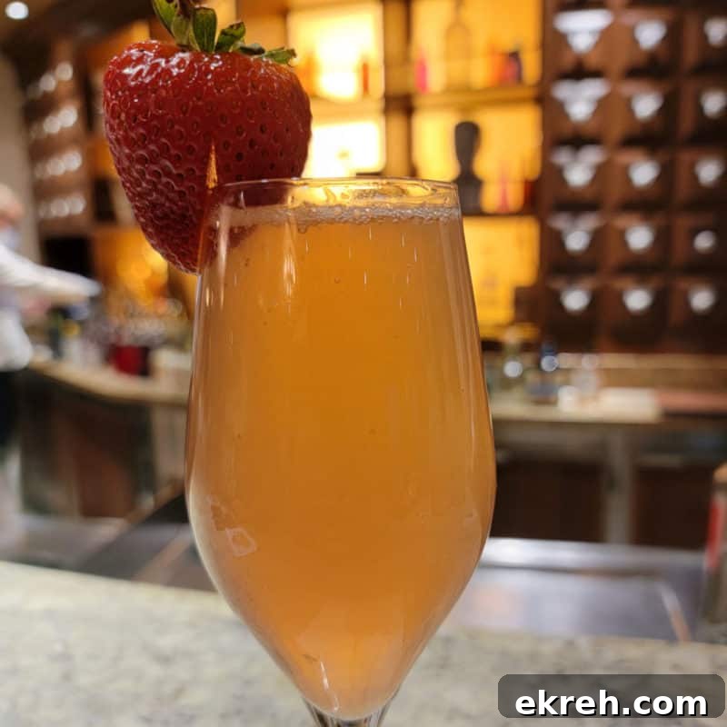 French Kiss Champagne cocktail with a strawberry garnish with the Alchemy bar in the background
