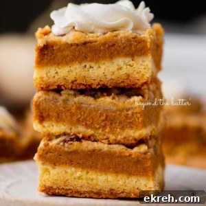 Stack of three pumpkin pie cake bars on a parchment paper lined bottom.