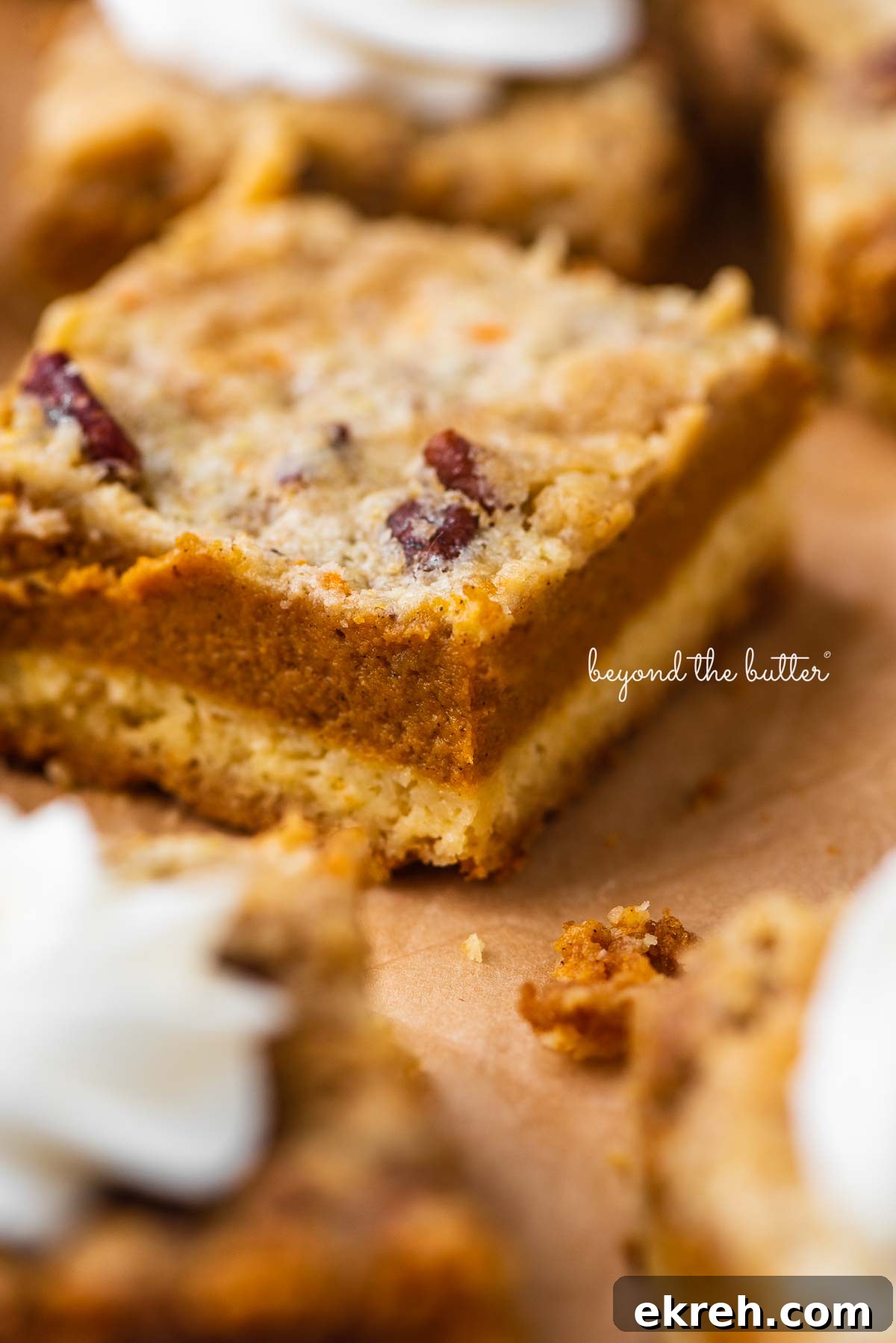 Pumpkin Pie Cake Bars Recipe 5 Sliced pumpkin pie cake bars on parchment paper background | © Beyond the Butter®