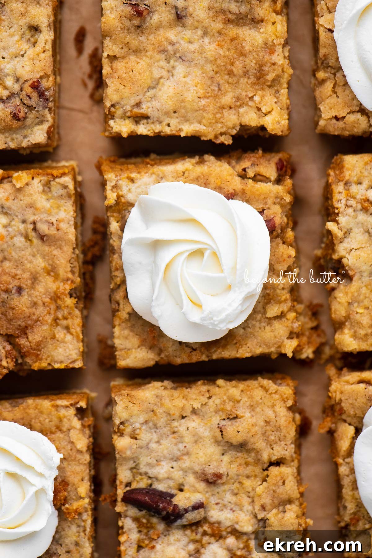 Pumpkin Pie Cake Bars Recipe 6 Sliced pumpkin pie cake bars on parchment paper background | © Beyond the Butter®