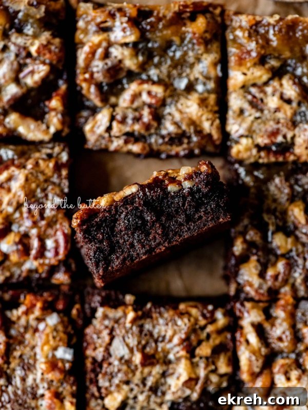 Pumpkin Pie Cake Bars Recipe 10 Salted pecan pie brownies placed on brown parchment paper with the center brownie placed on its side.