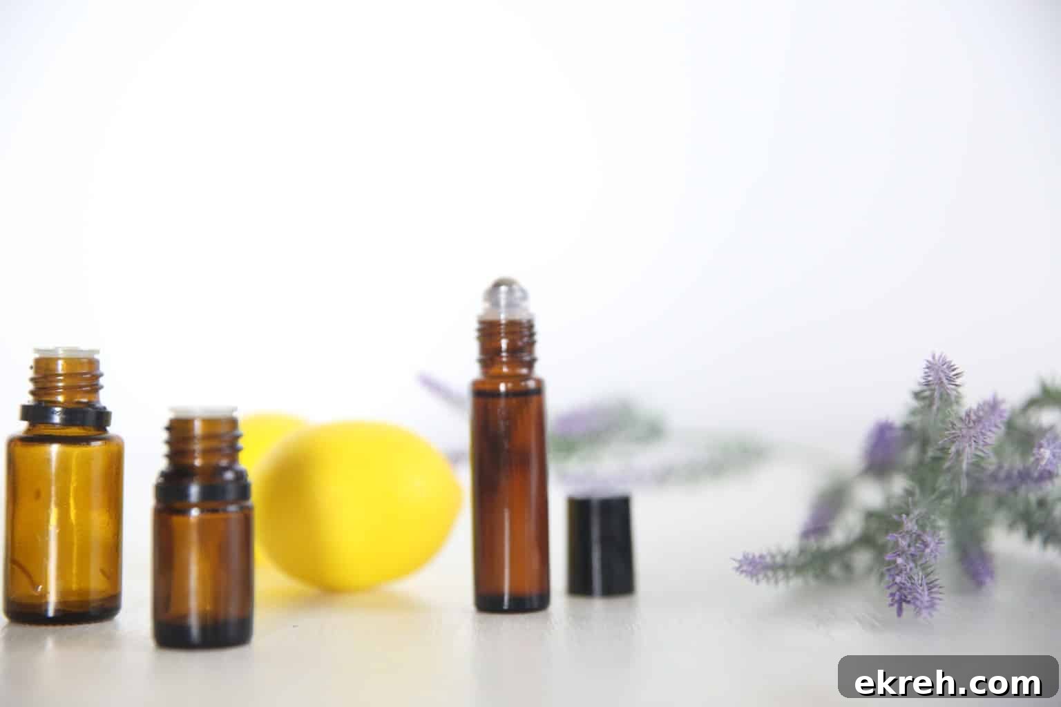 Lemon Lavender Peppermint Roller for Spring Aromatherapy 4 Essential oil bottles on white table with fresh lemons and lavender.