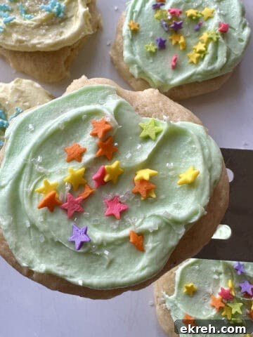 A frosted cookie on a spatula with more cookies on a plate.