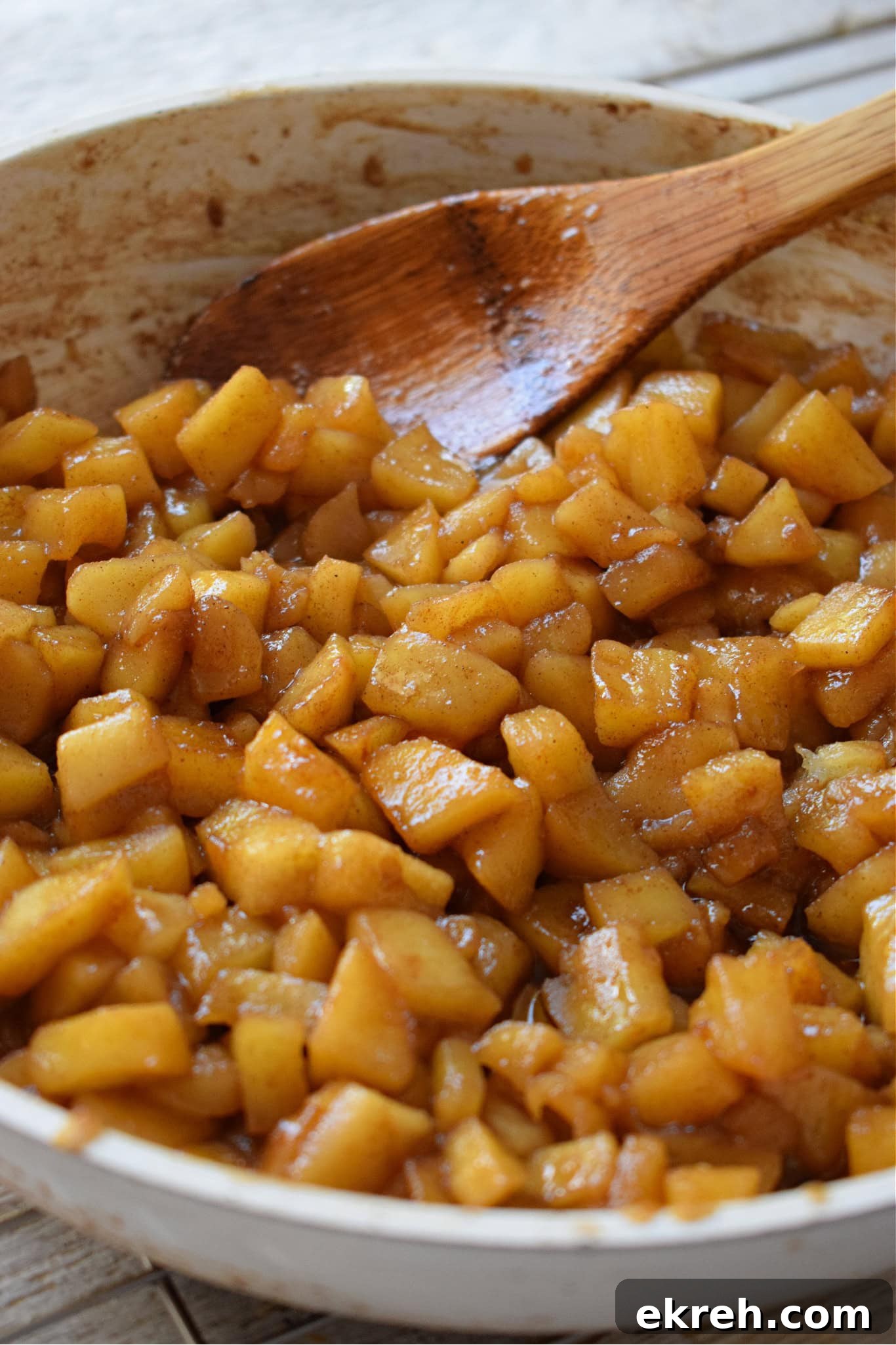 Cooked apples in a white skillet.