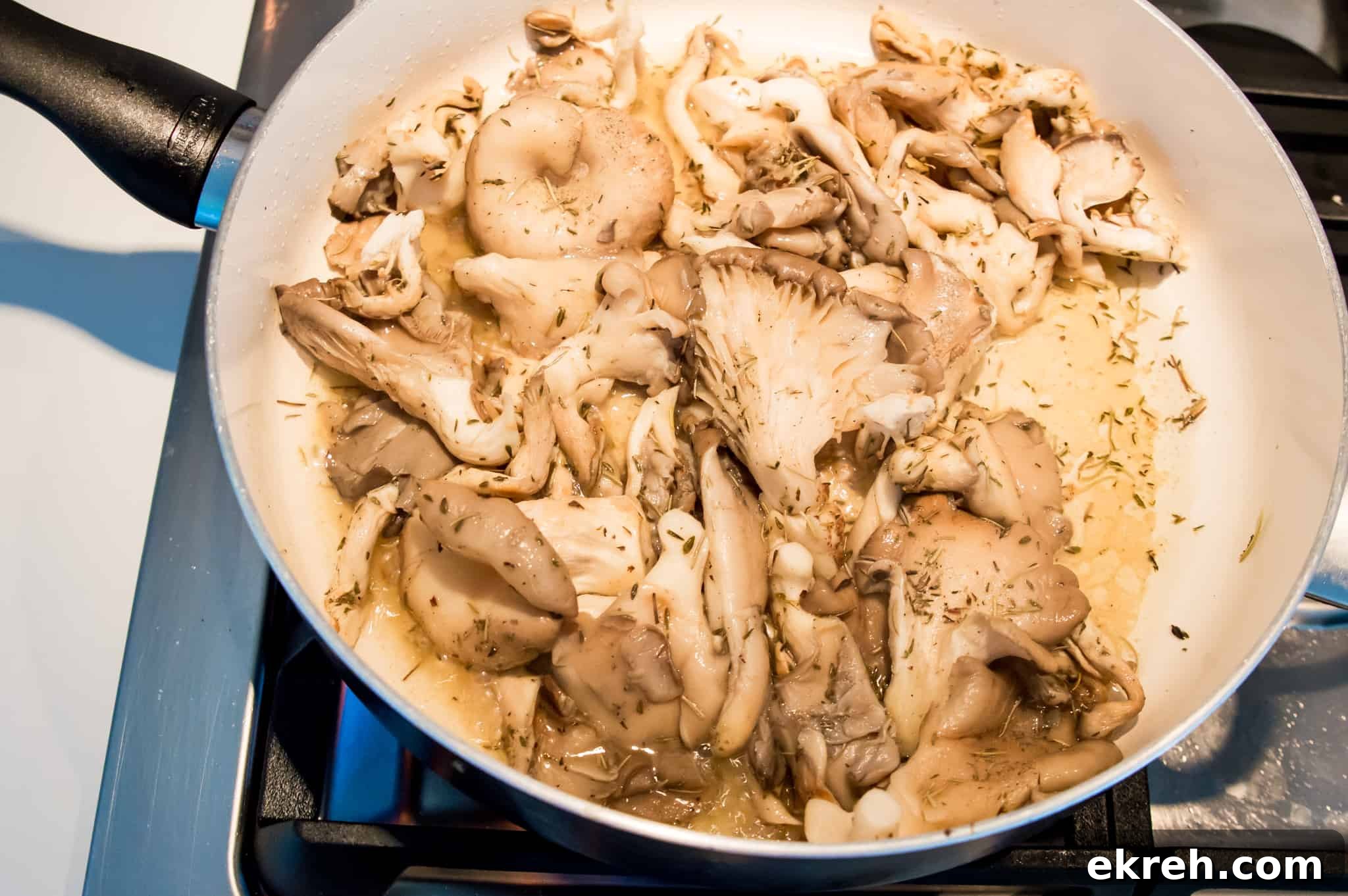 Oyster mushrooms cooking in a pan on the stovetop.