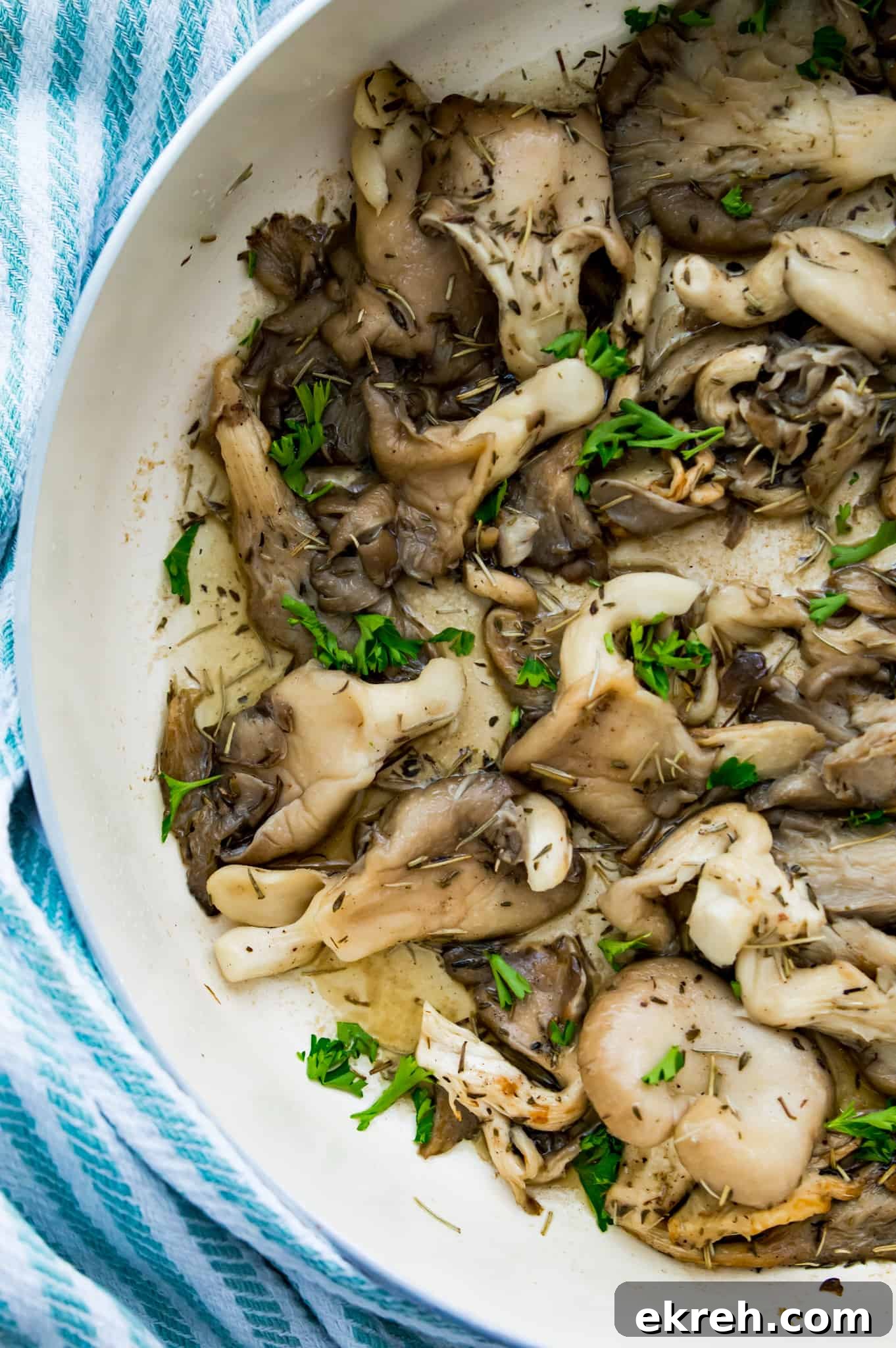 A pan of cooked oyster mushrooms with fresh herbs on top.