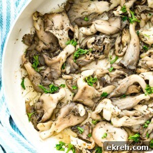 A pan of fried oyster mushrooms topped with fresh herbs.