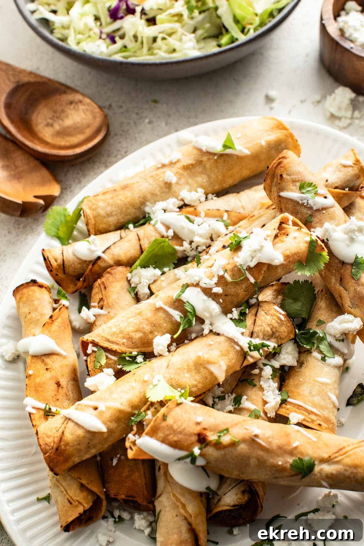 How to Make Crispy Air Fryer Chicken Taquitos 10 A plate of golden brown taquitos drizzled with sauce and cheese.