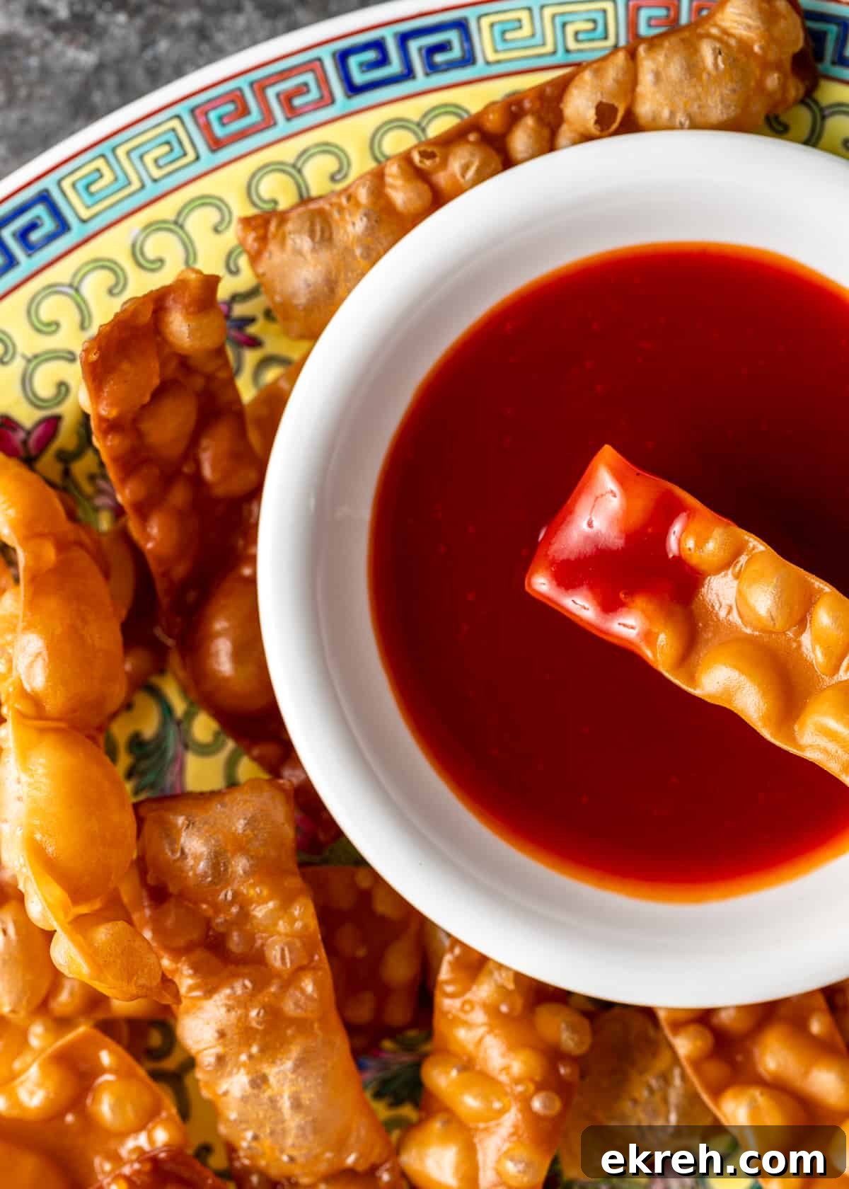 Homemade Sweet and Sour Sauce Recipe for Stir-Fries and Dipping 3 closeup overhead: white bowl of sweet and sour sauce with wonton strip dipped in sauce