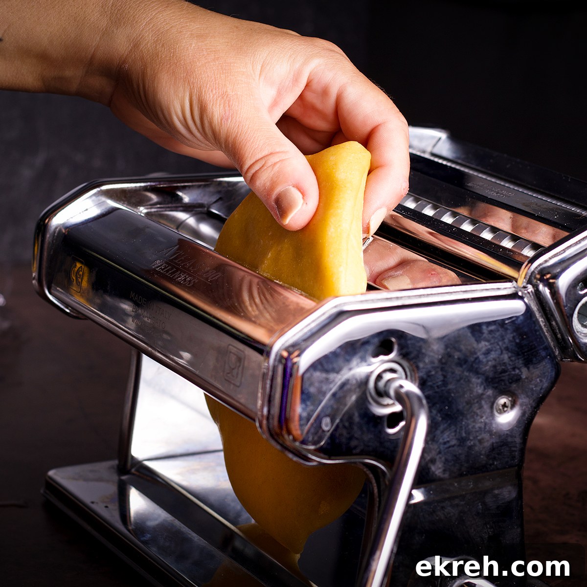 Feeding dough into a pasta machine on it's widest setting.