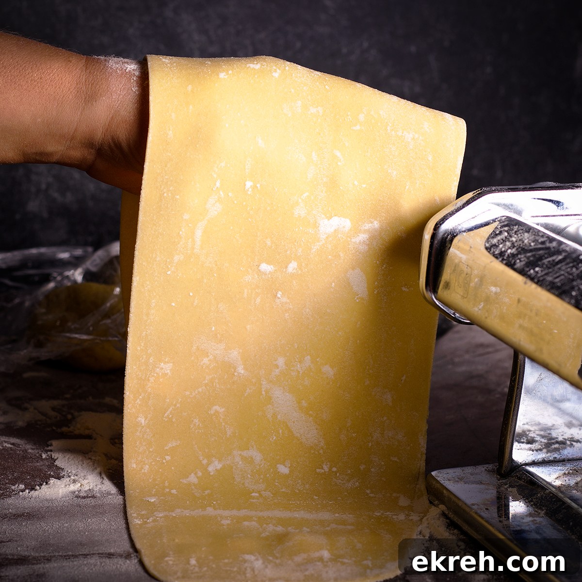 A sheet of pasta dough that's been rolled into a long sheet and is ready to be cut into spaghetti strands.