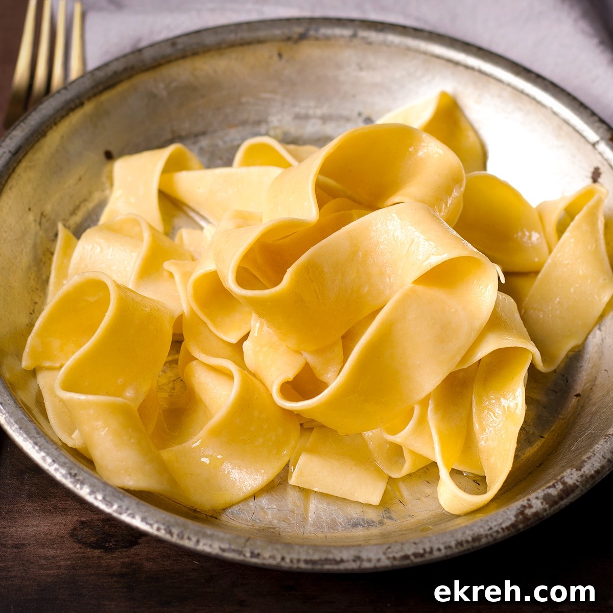A tin plate filled with freshly cooked homemade pappardelle noodles.