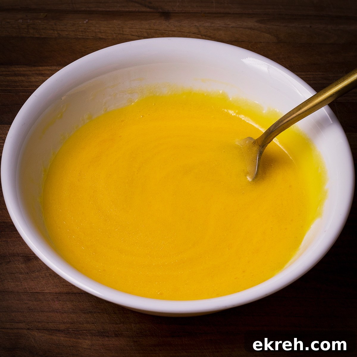 Using a fork to whisk one whole egg and six egg yolks in a bowl.