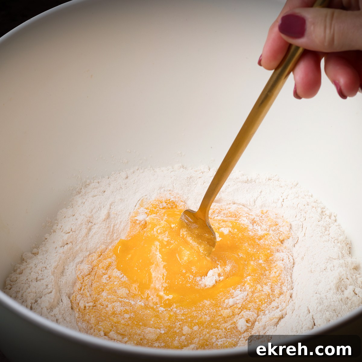Using a fork to slowly blend eggs into flour.