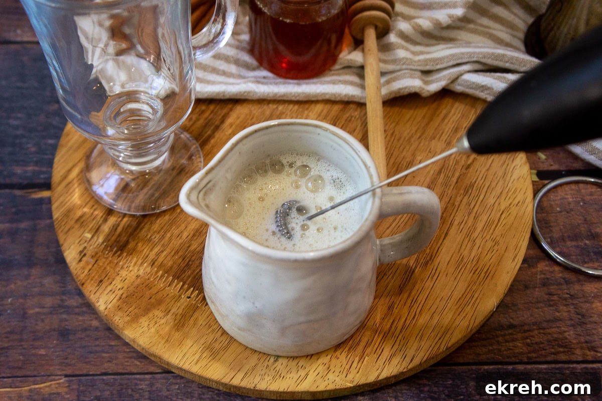 Creamy Oat Milk Honey Latte Recipe 4 a milk frother creating foam in a milk carafe.