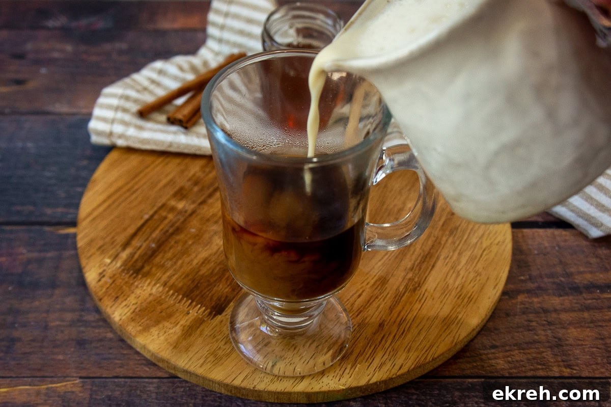 Creamy Oat Milk Honey Latte Recipe 5 cream being poured into a glass cup over hot espresso.